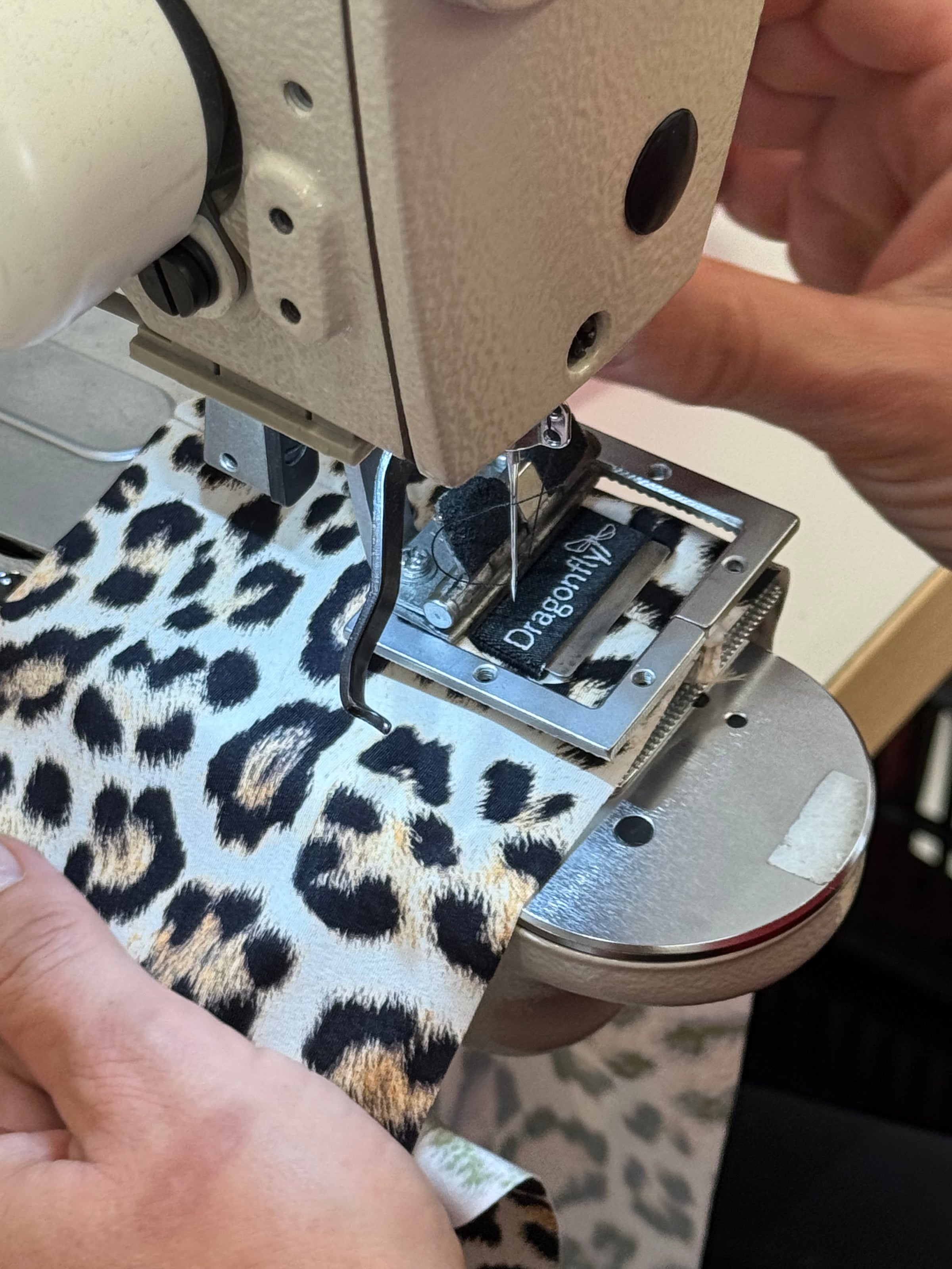 Close-up of a sewing machine needle and presser foot on a leopard prin fabric. Pole Wear production.
