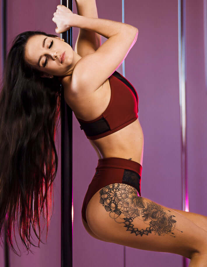 Model wearing mesh pole dance shorts demonstrating a pose on a pole, showcasing the design and fit.